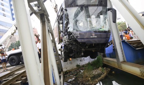 Petugas melakukan evakuasi bus Transjakarta yang mengalami kecelakaan di perlintasan kereta api Gunung Sahari, Jakarta, Kamis (19/5). 