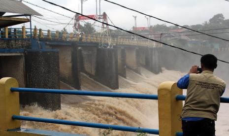 Petugas melakukan pemantauan saat debit air yang deras, di jembatan Bendung Katulampa, Kota Bogor, Jawa Barat, Jumat (19/2/2021). Tingginya intensitas curah hujan di kawasan Puncak, Bogor menyebabkan tinggi permukaan air di Bendung Katulampa mengalami kenaikan mencapai 100 cm atau siaga tiga sehingga warga yang berada di bantaran sungai Ciliwung, Jakarta harus mewaspadai terjadinya banjir.