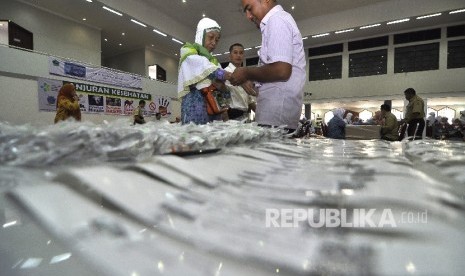 Petugas melakukan pemasangan gelang identitas calon jamaah haji kloter satu sebelum bersiap untuk berangkat ke tanah suci di Asrama Haji Pondok Gede, Jakarta, Kamis (27/7).