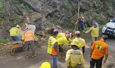 Petugas melakukan pembersihan sisa material longsor yang terjadi di jalan provinsi, tepatnya Kampung Sodong, Desa Keramatwangi, Kecamatan Cikajang, Kabupaten Garut, Senin (30/12). 