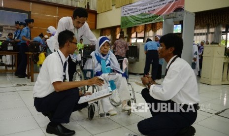 Petugas melakukan pemeriksaan Calon Jamaah Haji berkursi  roda asal Kabupaten Kuningan bersiap untuk berangkat ke Bandara Halim Perdanakusuma di Asrama Haji Embarkasi Jakarta Bekasi, Kota Bekasi, Jabar, Kamis (11/8). 