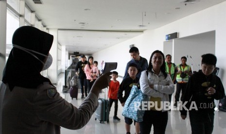 Petugas melakukan pendeteksi suhu tubuh (thermal scanner) saat penumpang pesawat tiba di terminal 2 Bandara Juanda Surabaya, Jawa Timur, Rabu (22/1/2020). 