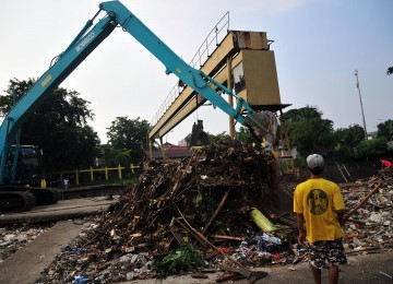 Petugas melakukan pengerukan sampah di Pintu Air Manggarai.