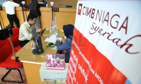 Petugas melayani nasabah di salah satu kantor cabang Bank CIMB Niaga Syariah, Jakarta, Senin (14/7). 