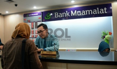 Petugas melayani nasabah di salah satu kantor cabang Bank Muamalat, Jakarta, Selasa (10/3).