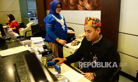 Petugas melayani nasabah menggunakan baju adat Bugis di Kantor Layanan Bank BRI, Jakarta, Jumat (21/4). 