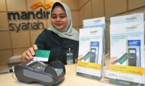 Petugas melayani transaksi nasabah dengan kartu ATM di kantor layanan Bank Syariah Mandiri, Jakarta, Rabu (21/5).