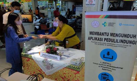 Petugas melayani warga yang mengalami kendala saat melakukan pemindaian kode batang sertifikat vaksin COVID-19 melalui aplikasi PeduliLindungi di swalayan Tiara Dewata, Denpasar, Bali, Sabtu (25/9/2021). Swalayan yang sudah menerapkan SOP PeduliLindungi sejak Selasa (14/9/2021) tersebut menyediakan pelayanan membantu mengunduh aplikasi PeduliLindungi untuk mengedukasi masyarakat karena hampir 75 persen konsumen mengalami kendala dan tidak paham cara mengakses aplikasi itu.