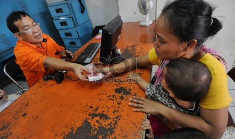   Petugas melayani warga yang mengambil uang Bantuan Langsung Sementara Masyarakat (BLSM) di Jakarta, Sabtu (22/6).  (Republika/Aditya Pradana Putra)