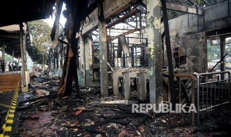  Petugas melintas di depan bangunan yang hangus terbakar di Stasiun Klender, Jakarta, Jumat (19/5).