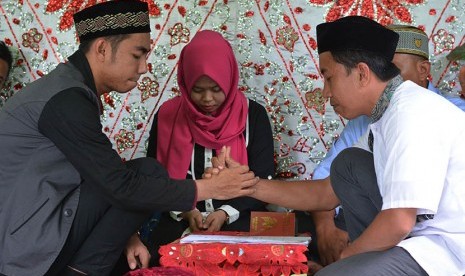 Petugas memandu akad nikah sepasang mempelai di Kantor Urusan Agama (KUA) Kecamatan Palu Selatan, Palu, Sulawesi Tengah, Kamis (22/12). 