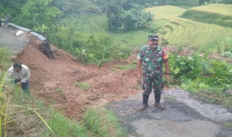 Petugas memantau jalan yang terbawa longsor di Desa Mekarbuana, Kecamatan Panawangan, Kabupaten Ciamis, Ahad (8/1/2023). 