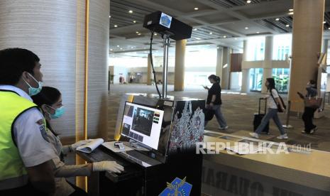 Petugas memantau suhu tubuh penumpang menggunakan alat pemindai suhu tubuh di Terminal Kedatangan Internasional Bandara Internasional I Gusti Ngurah Rai, Bali, Rabu (22/1/2020). 