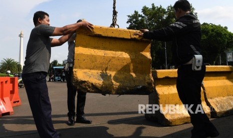 Petugas memasang beton pemisah jalan atau Moveble Concrete Barrier (MCB) di depan Istana Merdeka Jakarta, Kamis (14/2/2019). 