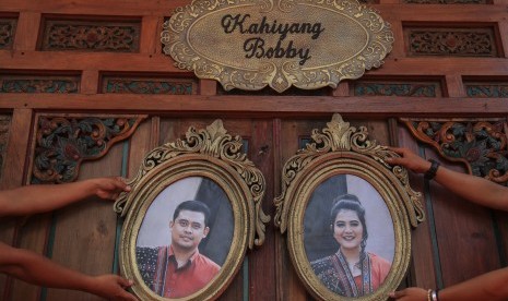 Petugas memasang foto putri Presiden Joko Widodo, Kahiyang Ayu (kanan) dengan Bobby Nasution (kiri) saat menyelesaikan dekorasi pernikahannya di Gedung Graha Saba, Solo, Jawa Tengah, Senin (6/11).