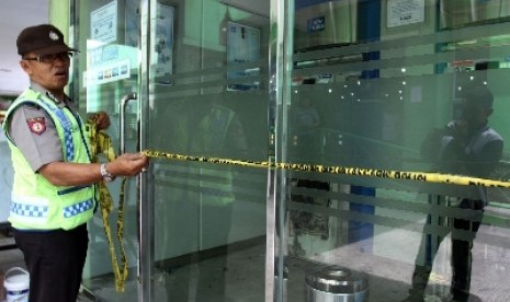 Petugas memasang garis polisi di lokasi ATM BCA yang dibobol maling. 