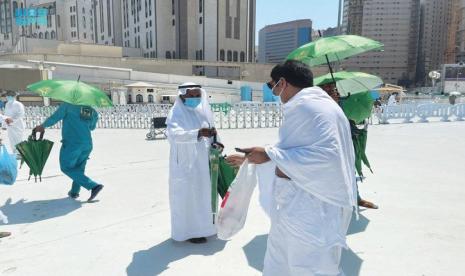 Petugas membagikan payung pada jamaah di Masjidil Haram, Makkah, Arab Saudi.