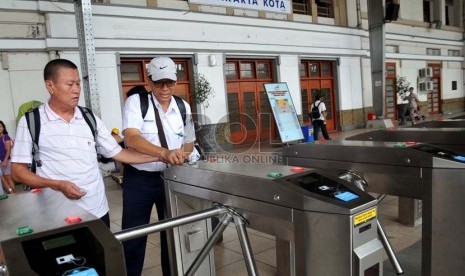  Petugas membantu calon penumpang kereta api listrik (KRL)  menggunakan tiket elektronik (e-ticketing) di Stasiun Jakarta Kota, Selasa (23/4).    (Republika/Prayogi)