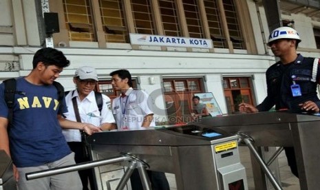 Petugas membantu calon penumpang kereta api listrik (KRL) menggunakan tiket elektronik (e-ticketing) di Stasiun Jakarta Kota, Selasa (23/4).