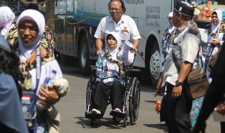 Petugas membantu jamaah calon haji kelompok terbang (kloter) 2 dari Kabupaten Bondowoso tiba di Asrama Haji Embarkasi Surabaya (AHES), Surabaya, Jawa Timur, Senin (16/7)