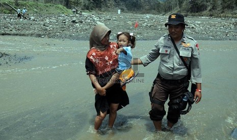 Petugas membantu mengevakuasi warga warga Desa Pandansari yang terputus akses jalannya akibat lahar dingin Gunung Kelud di Kecamatan Ngantang, Malang, Jawa Timur, Kamis (20/2).