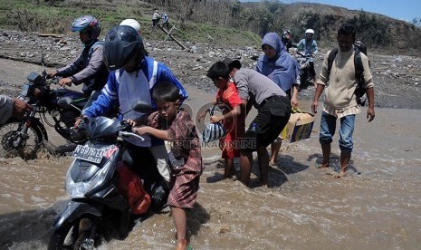 Petugas membantu mengevakuasi warga warga Desa Pandansari yang terputus akses jalannya akibat lahar dingin Gunung Kelud di Kecamatan Ngantang, Malang, Jawa Timur, Kamis (20/2).