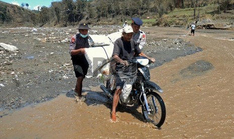 Petugas membantu mengevakuasi warga warga Desa Pandansari yang terputus akses jalannya akibat lahar dingin Gunung Kelud di Kecamatan Ngantang, Malang, Jawa Timur, Kamis (20/2).