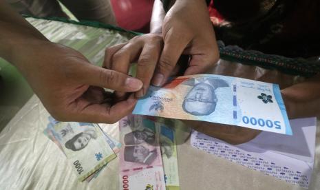 Petugas membantu penyandang tuna netra meraba uang rupiah saat sosialisasi keaslian uang rupiah di Balai Desa Ngebrak, Kediri, Jawa Timur, Sabtu (1/10/2022). Bank Indonesia kantor perwakilan Kediri melakukan sosialisasi ciri-ciri keaslian uang rupiah tahun emisi 2022 kepada difabel hingga tingkat desa. 