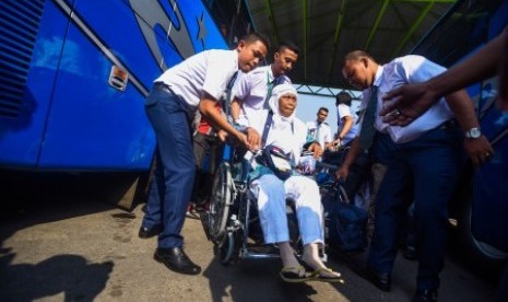 Petugas membantu seorang jamaah calon haji sebelum diberangkatkan ke Bandara Juanda menuju Mekah di Asrama Haji Sukolilo, Surabaya, Jawa Timur, Jumat (21/8). 