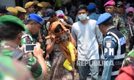   Petugas membantu warga eks anggota Gerakan Fajar Nusantara (Gafatar) yang baru turun dari KRI Banten saat tiba di Pelabuhan Kolinlamil Tanjung Priok, Jakarta Utara, Rabu (27/1) (Republika/Yasin Habibi).