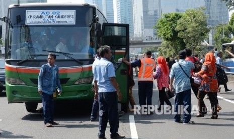 Petugas membantu warga mencarikan angkutan umum pengganti saat sopir taksi melakukan sweeping di Jalan Gatot Soebroto, Jakarta, Selasa (22/3). (Republika/Yasin Habibi)