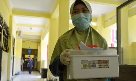 Petugas membawa boks berisi sampel urine milik pasien suspect ebola untuk dicek ke laboratorium di Rumah Sakit Umum Propinsi (RSUP) dr. Soedono Madiun, Jatim, Ahad (2/11). 