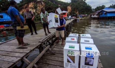 Petugas membawa kotak suara ketika melakukan pendistribusian logistik Pemilu 2019 di Kampung Kayu Pulo, Jayapura, Papua, Selasa (16/4/2019).