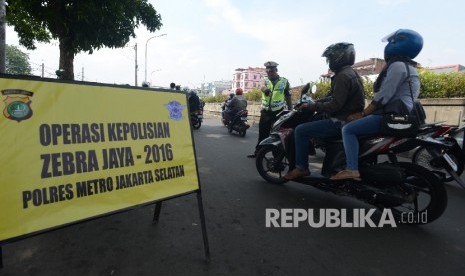 Petugas memberhentikan kendaraan untuk memeriksa kelengkapan surat kendaraan saat menggelar Operasi Zebra Jaya di Pasar Minggu, Kamis (17/11).