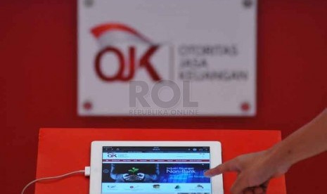 Petugas memberikan informasi mengenai Otoritas Jasa Keuangan (OJK) kapada pengunjung dalam pameran Indonesia Financial Expo & Forum (IFEF) 2014 di Jakarta Convention Center (JCC), Jumat (26/9).(Republika/Prayogi)