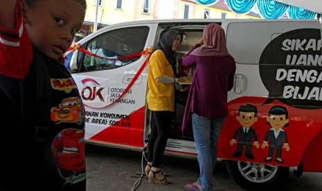 Petugas memberikan penyuluhan kepada warga saat peresmikan sosialisasi Si MObil LitErasi Keuangan (SiMOLEK) di Pasar Juanda, Bekasi, Jawa Barat, Senin (5/5).