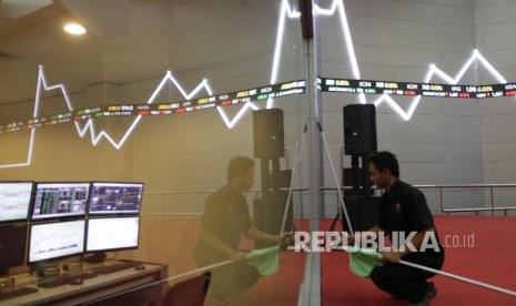 Petugas berdiri di dekat papan elektronik yang menunjukkan pergerakan indeks harga saham gabungan (IHSG) di gedung Bursa Efek Indonesia.