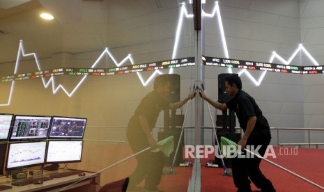 Petugas membersihkan di dekat papan elektronik yang menunjukkan pergerakan indeks harga saham gabungan (IHSG) di gedung Bursa Efek Indonesia, Jakarta, Kamis (7/9).