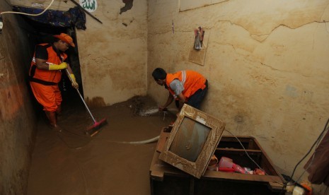 Petugas membersihkan endapan lumpur sisa banjir di perumahan Pengadegan, Jakarta, Kamis (2/1/2020). Banjir yang melanda permukiman warga di kawasan tersebut berangsur surut, dan warga mulai membersihkan rumah dari endapan lumpur sejak banjir menggenangi rumah. 