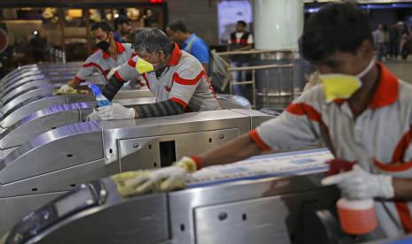 Petugas membersihkan gerbang otomatis stasiun metro di New Delhi, India, Jumat (13/3). Disinfeksi dilakukan sebagai upaya pencegahan virus corona di India.