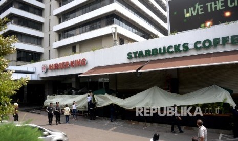 Petugas membersihkan pecahan kaca bekas ledakan di Starbucks Coffe, Jakarta, Jumat (15/1).