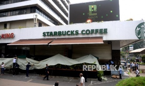 Petugas membersihkan pecahan kaca bekas ledakan di Starbucks Coffe, Jakarta, Jumat (15/1). 