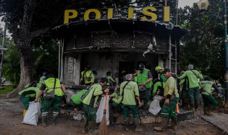 Petugas membersihkan pos polisi yang rusak pasca aksi tolak pengesahan Omnibus Law Undang-Undang Cipta Kerja.