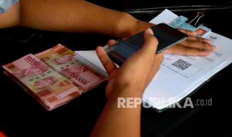 Petugas memeriksa formulir penerima bantuan saat Penyaluran Bantuan Sosial Tunai (BST)