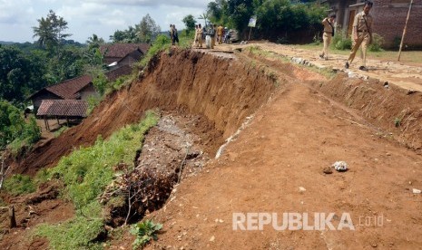 Petugas memeriksa jalan desa yang ambrol terseret longsor di Desa Sidomulyo, Tulungagung, Jawa Timur, Senin (8/4/2019).