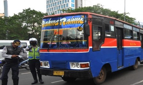 Petugas memeriksa kelengkapan surat kendaraan sopir Metro Mini saat razia gabungan angkutan umum di Jalan Sudirman, Jakarta, Senin (7/12). (Republika/Yasin Habibi)