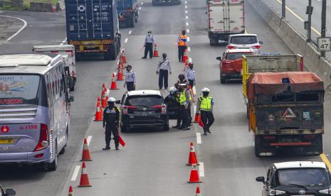 Petugas memeriksa kendaraan roda empat di Jalan tol Jakarta - Cikampek Km 47, Karawang, Jawa Barat, Rabu (6/5/2020). Penyekatan akses transportasi di tol Jakarta - Cikampek tersebut sebagai tindak lanjut kebijakan larangan mudik dan Pembatasan Sosial Berskala Besar (PSBB) guna memutus mata rantai penyebaran Covid-19. 