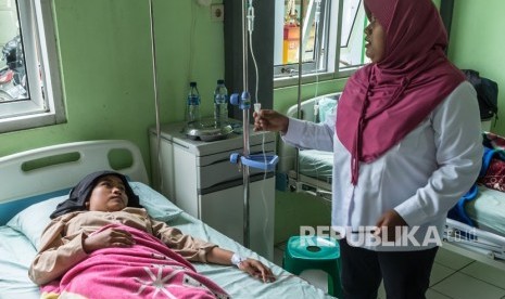 Petugas memeriksa seorang pelajar yang diduga keracunan.