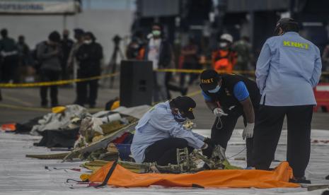 Petugas memeriksa serpihan bagian pesawat Sriwijaya Air SJ182 rute Jakarta - Pontianak yang jatuh di perairan Pulau Seribu di Dermaga JICT, Tanjung Priok, Jakarta Utara, Ahad (10/1).