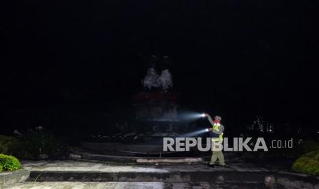 Petugas memeriksa situasi area ruang publik menggunakan senter saat berpatroli di Lapangan Puputan Badung, Denpasar, Bali, Jumat (31/12/2021) malam. Direktur Distribusi PLN Adi Priyatno memprediksi beban puncak penggunaan listrik saat tahun baru di wilayah Bali mencapai 920 megawatt.